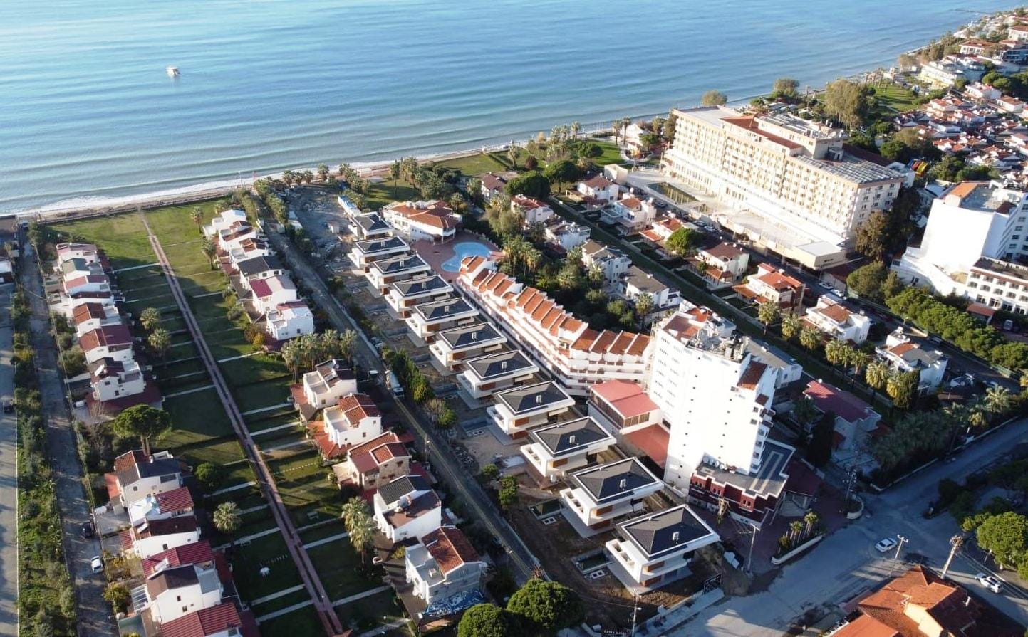 Aerial view of a beachside Turkish development with detached villas and a hotel on the Aegean coast